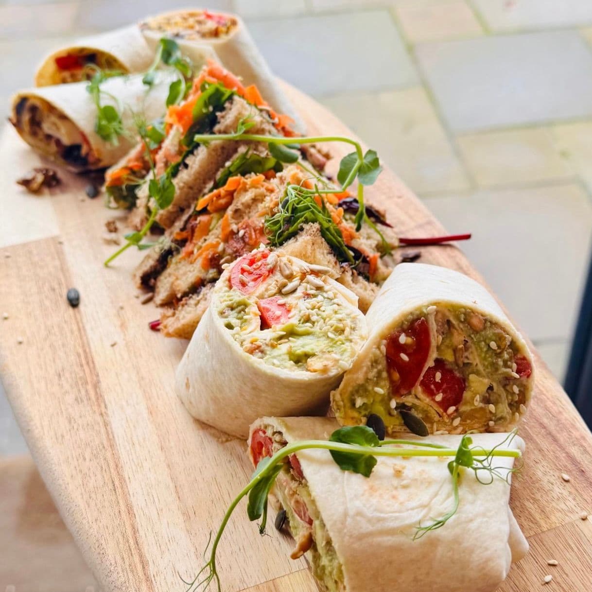 Selection of freshly prepared wraps and sandwiches on a wooden serving board